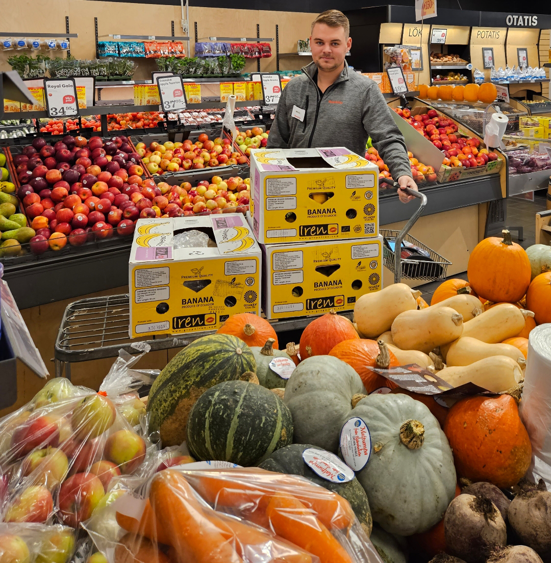 En glad manlig medarbetare står vid fruktdisken i en Hemköpbutik i Rydebäck