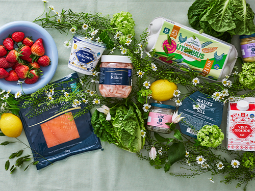 Ett bord med midsommarvaror som ägg, jordgubbar, citron, räkor, grädde, sill, lax, gräddfil och knäckebröd.