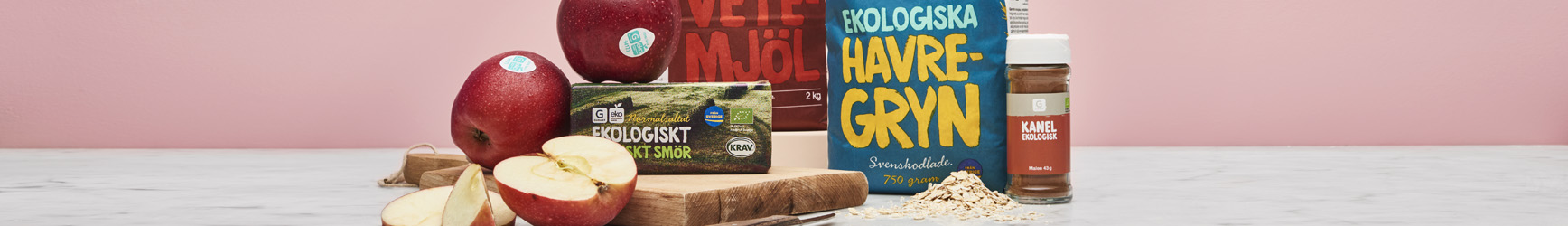 Stilleben av blandade ekologiska varor som står på ett ljust marmor bord, och en rosa bakgrund